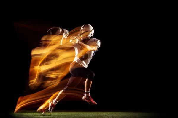 Genç bir adamın portresi, Amerikan futbolcu eğitimi karanlık stüdyo arka planında izole edilmiş, karışık neon ışıklı. Spor, rekabet ve güzellik kavramı — Stok fotoğraf