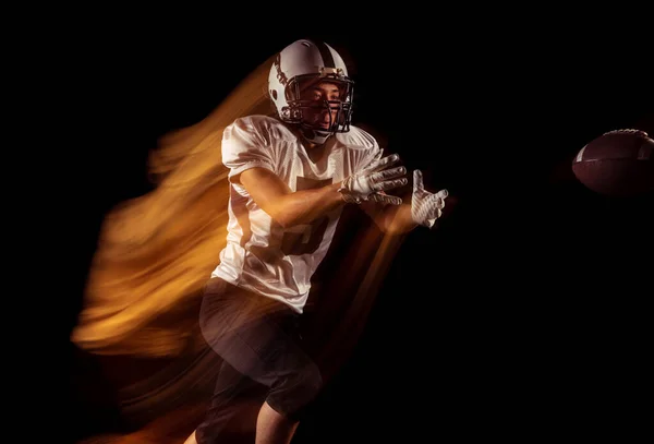Retrato de jovem, jogador de futebol americano treinando isolado em estúdio escuro com luz de néon mista. Conceito de esporte, competição e beleza — Fotografia de Stock