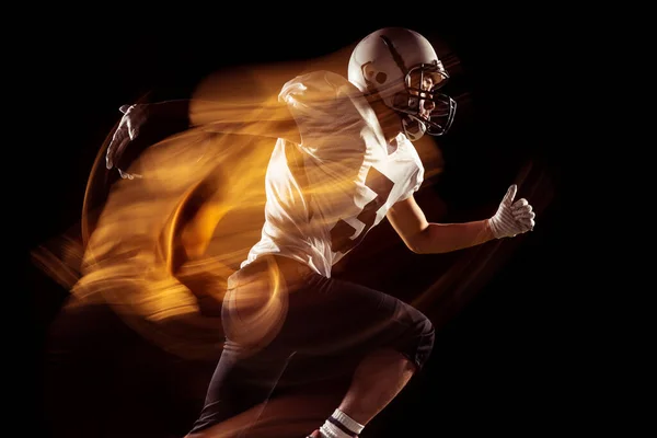 Portrait of young man, American football player training isolated on dark studio background with mixed neon light. Concept of sport, competition and beauty — Stock Photo, Image