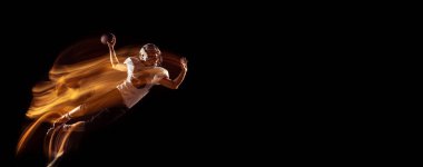 Amerikalı futbolcu eğitimi almış genç bir adamla el ilanı. Karanlık stüdyo arka planında izole edilmiş ve karışık neon ışığı var. Spor, rekabet ve güzellik kavramı