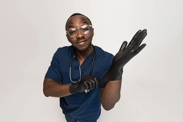 Retrato de joven médico africano, consejero terapéutico o médico en el trabajo. Poner guantes protectores en Concepto de salud, medicina del cuidado y humor. Primer plano — Foto de Stock
