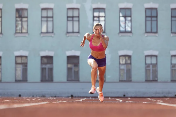 Leader, champion. Une femme caucasienne, athlète féminine, coureuse s'entraînant au stade public, au terrain de sport ou au terrain de jeu en plein air. Jeux de sport d'été. — Photo