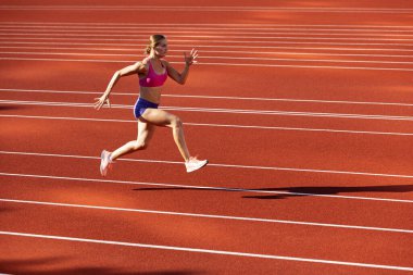 Beyaz bir kadın, bayan sporcu, stadyumda, spor salonunda ya da dışarıda koşucu eğitimi almış. Yaz sporu oyunları.