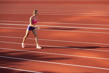 Beyaz bir kadın, bayan sporcu, stadyumda, spor salonunda ya da dışarıda koşucu eğitimi almış. Yaz sporu oyunları.