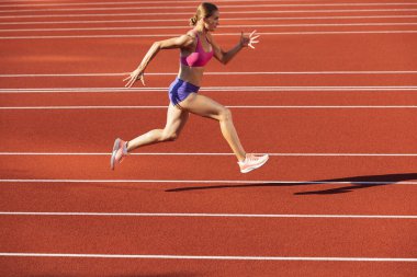 Beyaz bir kadın, bayan sporcu, stadyumda, spor salonunda ya da dışarıda koşucu eğitimi almış. Yaz sporu oyunları.