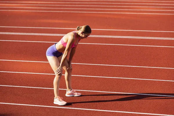 Una mujer caucásica, atleta, entrenadora de corredores en el estadio público, cancha deportiva o palyground al aire libre. Juegos de verano deporte. — Foto de Stock