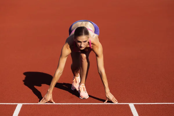 Na starcie. Jedna kobieta rasy kaukaskiej, atletka, trenerka biegaczy na stadionie, boisku sportowym lub na placu zabaw na świeżym powietrzu. Letnie gry sportowe. — Zdjęcie stockowe