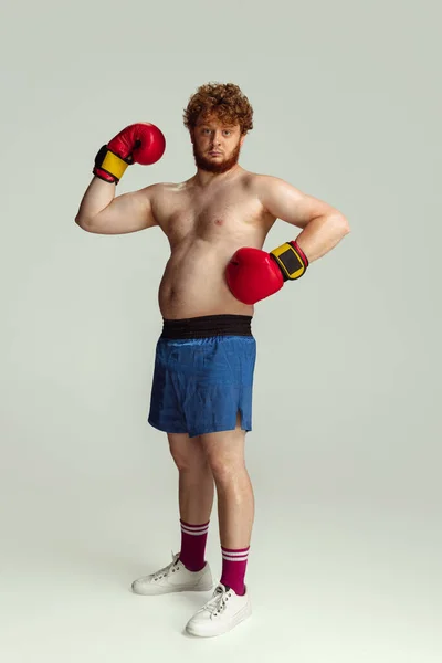 Grappige roodharige man in blauwe boksbroek en handschoenen geïsoleerd op grijze studio achtergrond. Concept van sport, humor en lichaam positief. — Stockfoto