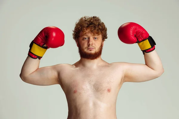 Homme roux drôle en short de boxe bleu et gants isolés sur fond de studio gris. Concept de sport, humour et corps positif. — Photo