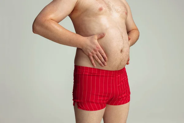 Detailní záběr tlusté mužské břicho, břicho izolované na šedém pozadí studia. Pojetí sportu, hubnutí, problémy s obezitou. — Stock fotografie