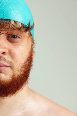 Yüzme şapkalı kızıl saçlı adamın gri stüdyo arka planında izole edilmiş görüntüsü. Spor anlayışı, mizah ve beden pozitif.