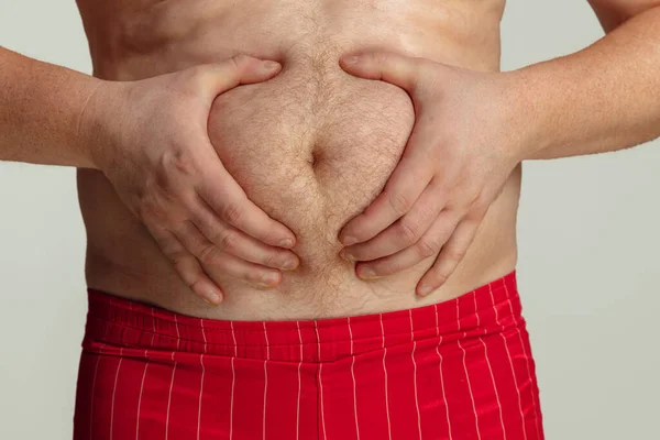 Detailní záběr tlusté mužské břicho, břicho izolované na šedém pozadí studia. Pojetí sportu, hubnutí, problémy s obezitou. — Stock fotografie