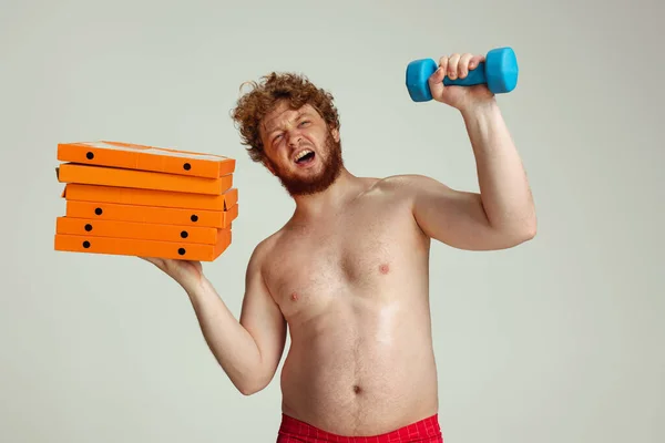 Homem ruivo bonito em shorts de natação vermelho posando isolado no fundo do estúdio cinza. Conceito de esporte, humor e corpo positivo. — Fotografia de Stock