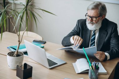 Yaşlı gri saçlı bir adamın portresi, profesör, öğretmen öğrencilerin ödevlerini kontrol ediyor sınıfta, içeride. Meslek mesleği, iş, eğitim kavramı