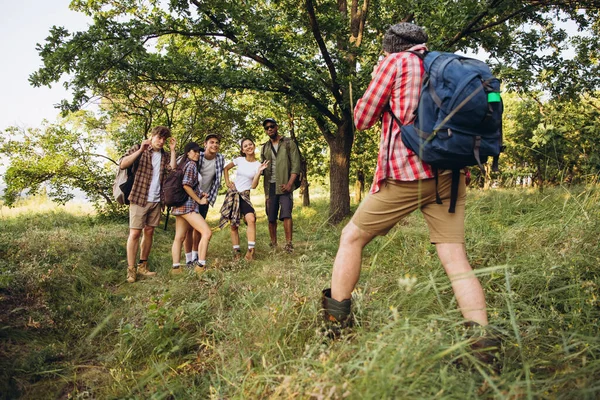 Group of friends, young men and women walking, strolling together during picnic in summer forest, meadow. Lifestyle, friendship, — Stock Photo, Image