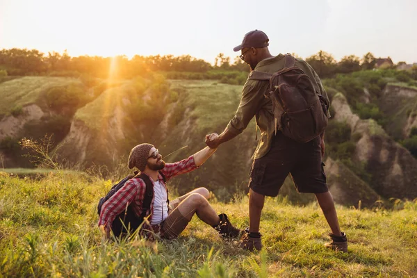 Jeunes hommes, amis marchant, se promenant ensemble en périphérie de la ville, dans la forêt d'été. Style de vie actif, voyage, concept de soutien — Photo