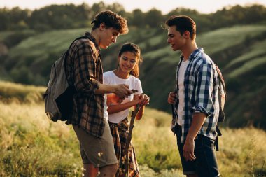 Bir grup arkadaş, genç erkekler ve kadınlar yaz ormanlarında piknik yaparken, çayırda yürüyorlar. Yaşam tarzı, arkadaşlık.,