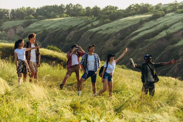 Grupo de amigos, jovens e mulheres caminhando, passeando juntos durante piquenique na floresta de verão, prado. Estilo de vida, amizade — Fotografia de Stock