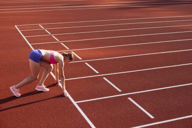 Başlangıç çizgisinde. Beyaz bir kadın, bayan sporcu, stadyumda koşucu eğitimi, spor sahası ya da açık havada koşu pisti. Yaz sporu oyunları.