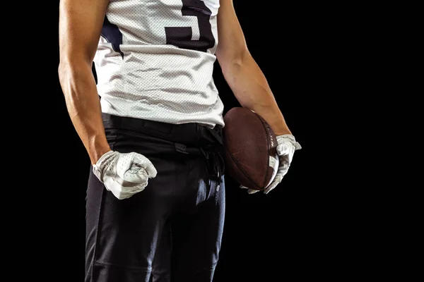 Imagem recortada de um jogador de futebol americano em capacete de equipamento esportivo e luvas isoladas em fundo de estúdio escuro em luz de néon. Conceito de desporto, competição — Fotografia de Stock