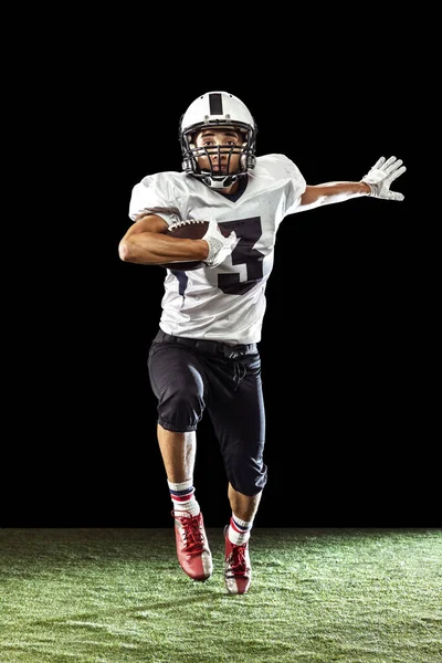 Ritratto di giocatore di football americano formazione isolato su sfondo scuro studio con pavimento in erba. Concetto di sport, competizione, obiettivi, risultati — Foto Stock
