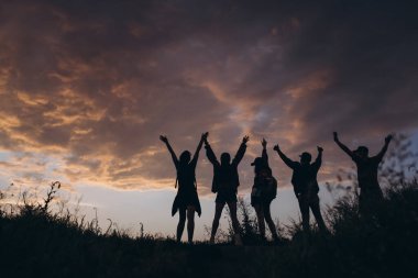 İnsanların siluetleri, genç adam ve kadınların gün batımıyla dışarıda, yaz ormanlarında, çayırlarda buluşması. Aktif yaşam tarzı, arkadaşlık, bakım, ekoloji kavramı