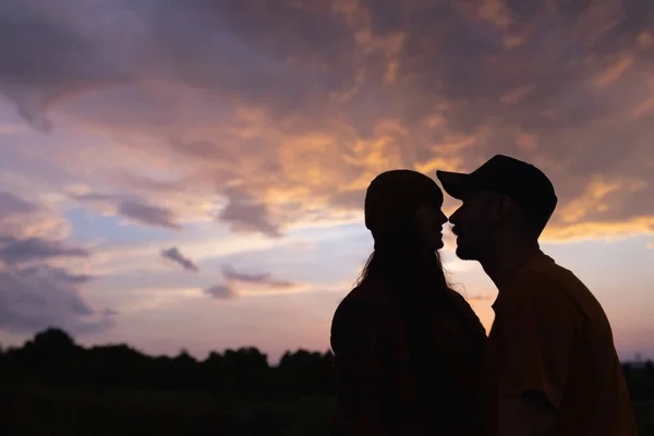Silhouettes fiatal férfi és nő találkozik naplemente szabadban, a nyári erdőben, rét. Aktív életmód, barátság, szeretet, gondozás, ökológia koncepció — Stock Fotó
