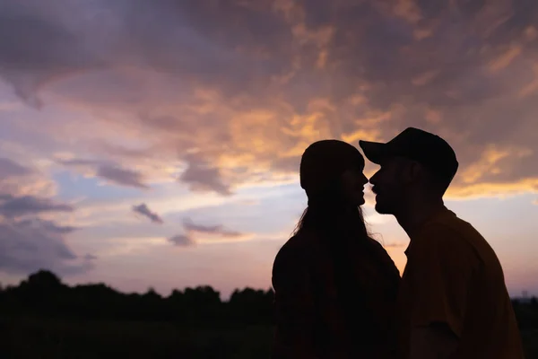 Silhouette di giovane uomo e donna che incontrano il tramonto all'aperto, nella foresta estiva, prato. Stile di vita attivo, amicizia, amore, cura, ecologia concetto — Foto Stock