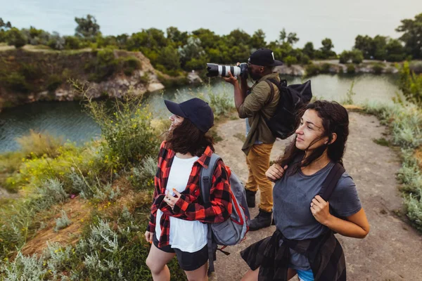 Groupe d'amis, jeunes hommes et femmes marchant, se promenant ensemble en périphérie de la ville, dans la forêt d'été, prairie. Style de vie actif, amitié, soins, concept écologique — Photo