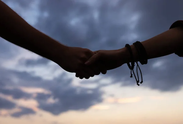 Silhouettes of male and female hands holding each other with love, support and loyalty isolated over night cloudy sky. Healthy lifestyle, friendship, love, care, beauty concept — Stock Photo, Image