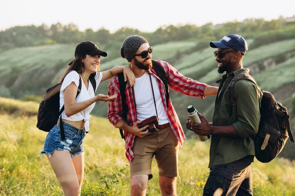 Group of friends, young men and woman walking, strolling together in summer forest, meadow. Active lifestyle, friendship, travel concept — Stock Photo, Image