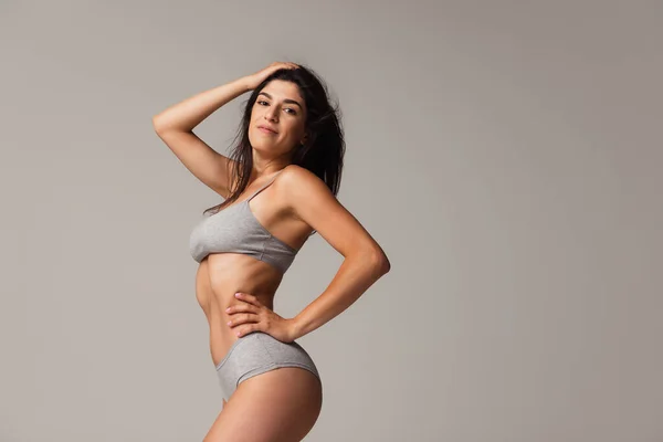 Retrato de una joven hermosa y delgada mujer en lencería posando aislada sobre un fondo gris de estudio. Concepto de belleza natural. — Foto de Stock