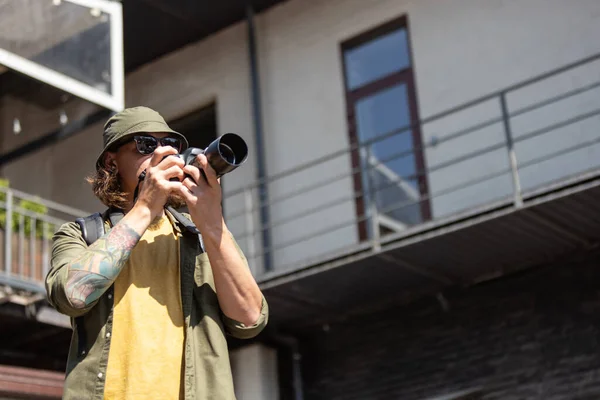 Portrait de jeune homme, photographe, caméraman avec appareil photo professionnel, équipement pendant la journée de travail d'été à l'extérieur. Notion de profession, d'emploi, d'éducation — Photo