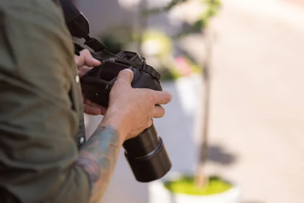 Close-up of young man, photographer, cameraman with professional camera, equipment during working summer day outdoors. Concept of occupation, job, education — Stock Photo, Image