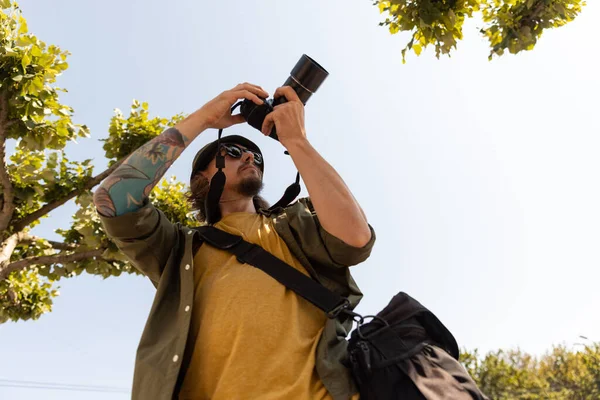 Portrait de jeune homme, photographe, caméraman avec appareil photo professionnel, équipement pendant la journée de travail d'été à l'extérieur. Notion de profession, d'emploi, d'éducation — Photo