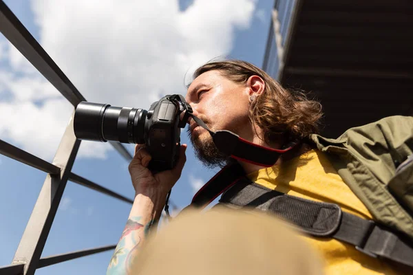 Portrait de jeune homme, photographe, caméraman avec appareil photo professionnel, équipement pendant la journée de travail d'été à l'extérieur. Notion de profession, d'emploi, d'éducation — Photo