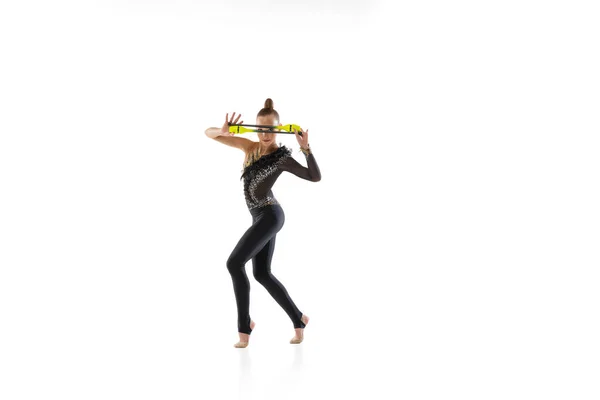 Una chica caucásica, artista de gimnasia rítmica practicando con bastón aislado sobre fondo blanco del estudio. Concepto de deporte, acción, aspiración, educación, estilo de vida activo — Foto de Stock