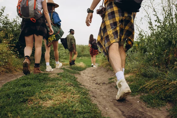Groupe d'amis, jeunes hommes et femmes marchant, se promenant ensemble en périphérie de la ville, dans la forêt d'été, prairie. Style de vie actif, amitié, soins, concept écologique — Photo