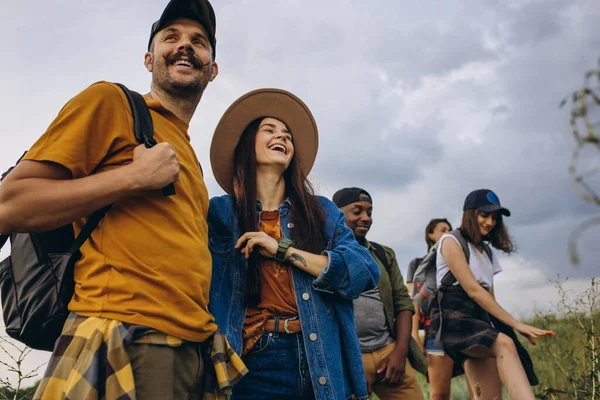 Group of friends, young men and women walking, strolling together outskirts of city, in summer forest, meadow. Active lifestyle, friendship, care, ecology concept — Stock Photo, Image