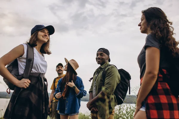 Group of friends, young men and women walking, strolling together outskirts of city, in summer forest, meadow. Active lifestyle, friendship, care, ecology concept — Stock Photo, Image