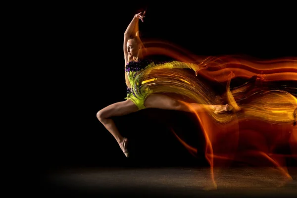 Портрет молодой девушки, художника художественной гимнастики в действии изолирован на темном студийном фоне со смешанным светом. Мбаппе о спорте, экшне, красоте — стоковое фото