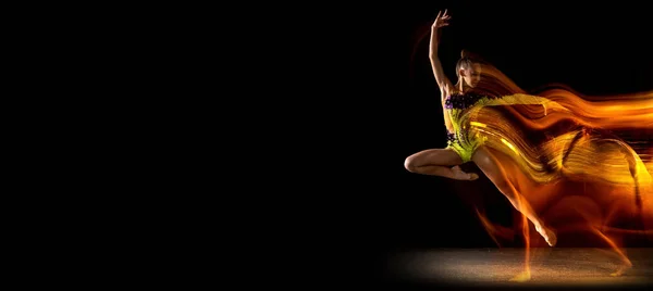 Флайер. Портрет молодой девушки, художника художественной гимнастики в действии изолирован на темном студийном фоне со смешанным светом. Мбаппе о спорте, экшне, красоте — стоковое фото
