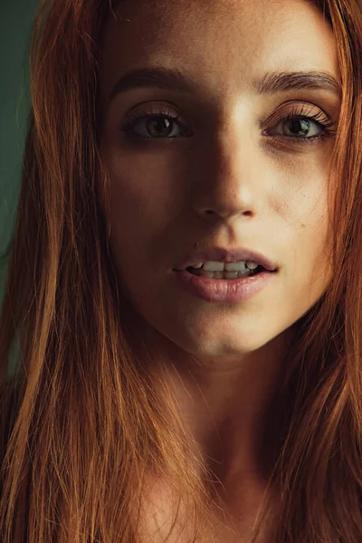 Retrato de close-up de jovem bela mulher ruiva sem maquiagem isolada sobre fundo de estúdio verde escuro. Conceito de beleza natural. — Fotografia de Stock