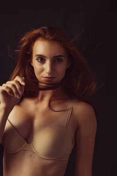 Fiatal gyönyörű karcsú, cserzett vörös hajú nő fehérneműben pózol elszigetelve sötét stúdió hátterében. Természetes szépség fogalma. — Stock Fotó