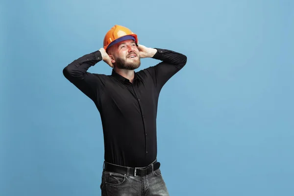 Retrato de hombre barbudo divertido, constructor, diseñador o arquitecto con equipo profesional aislado sobre fondo de estudio azul. —  Fotos de Stock