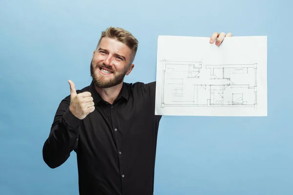 Porträt eines lustigen bärtigen Mannes, Bauunternehmers, Designers oder Architekten mit professioneller Ausstattung isoliert auf blauem Studiohintergrund. — Stockfoto