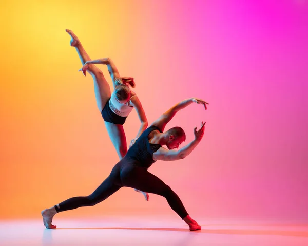 네온 빛의 다채 로운 노란색 배경 위에서 현대 춤을 추는 두 명의 댄서들, 멋진 운동화를 추는 남녀 모델들. — 스톡 사진