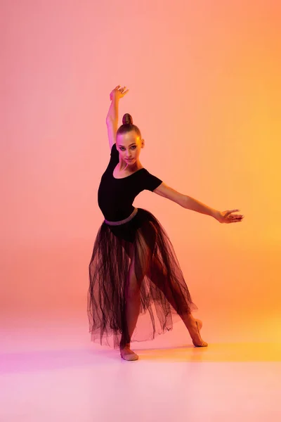 Une jeune fille, artiste de gymnastique rythmique en tenue de scène, costume de sport isolé sur fond studio jaune rose au néon. Concept de sport — Photo