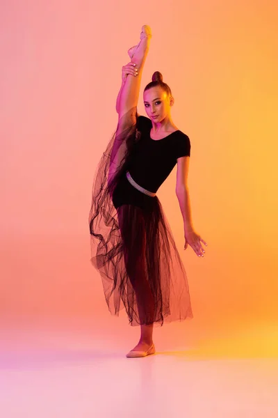 Une jeune fille, artiste de gymnastique rythmique en tenue de scène, jupe isolée sur fond studio jaune rose au néon. Concept de sport — Photo