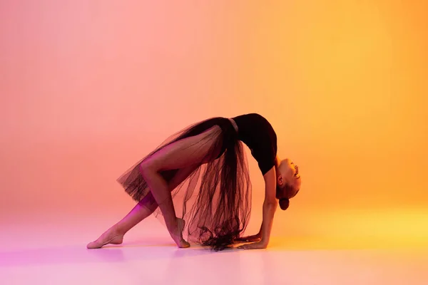 Retrato de niña, artista de gimnasia rítmica aislado sobre fondo de estudio amarillo rosado en neón. Concepto de deporte, acción, aspiración, educación, estilo de vida activo — Foto de Stock